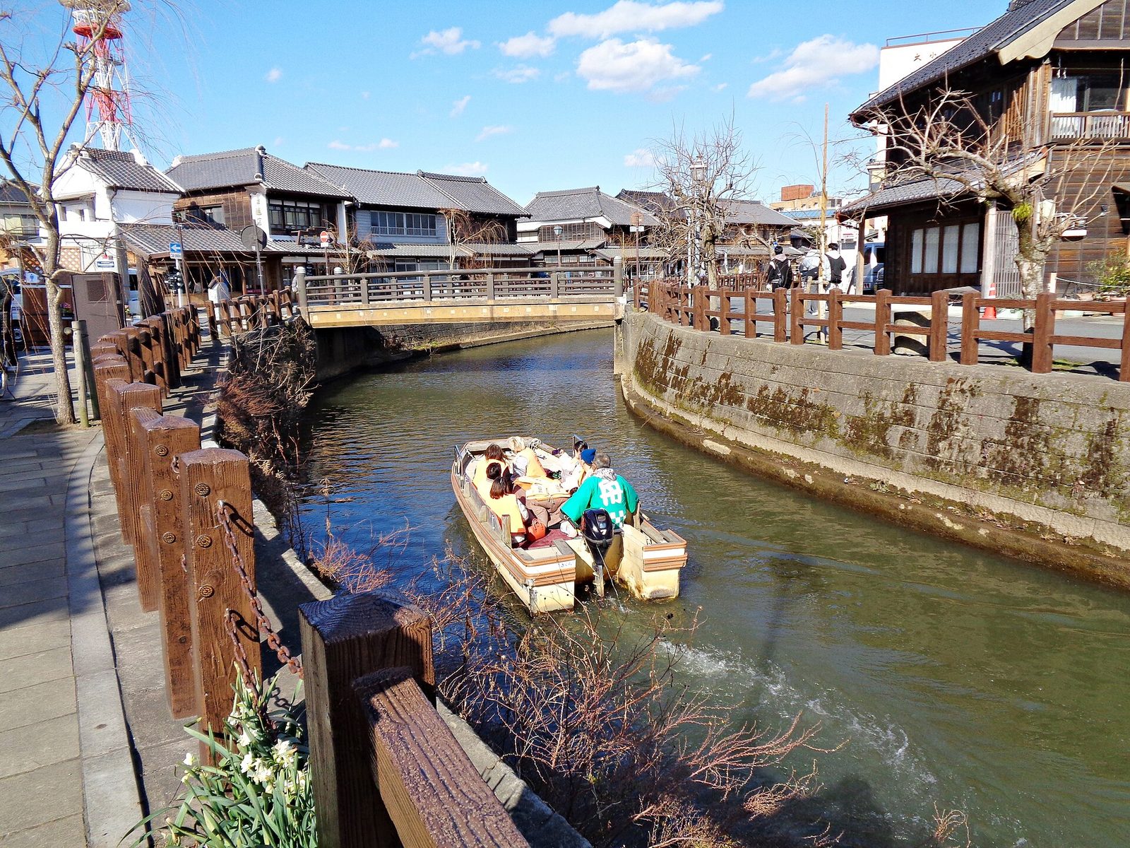 เรือนำเที่ยวแล่นในคลองของย่านซาวาระ มีบ้านเรือนแบบเก่าเรียงริมน้ำ